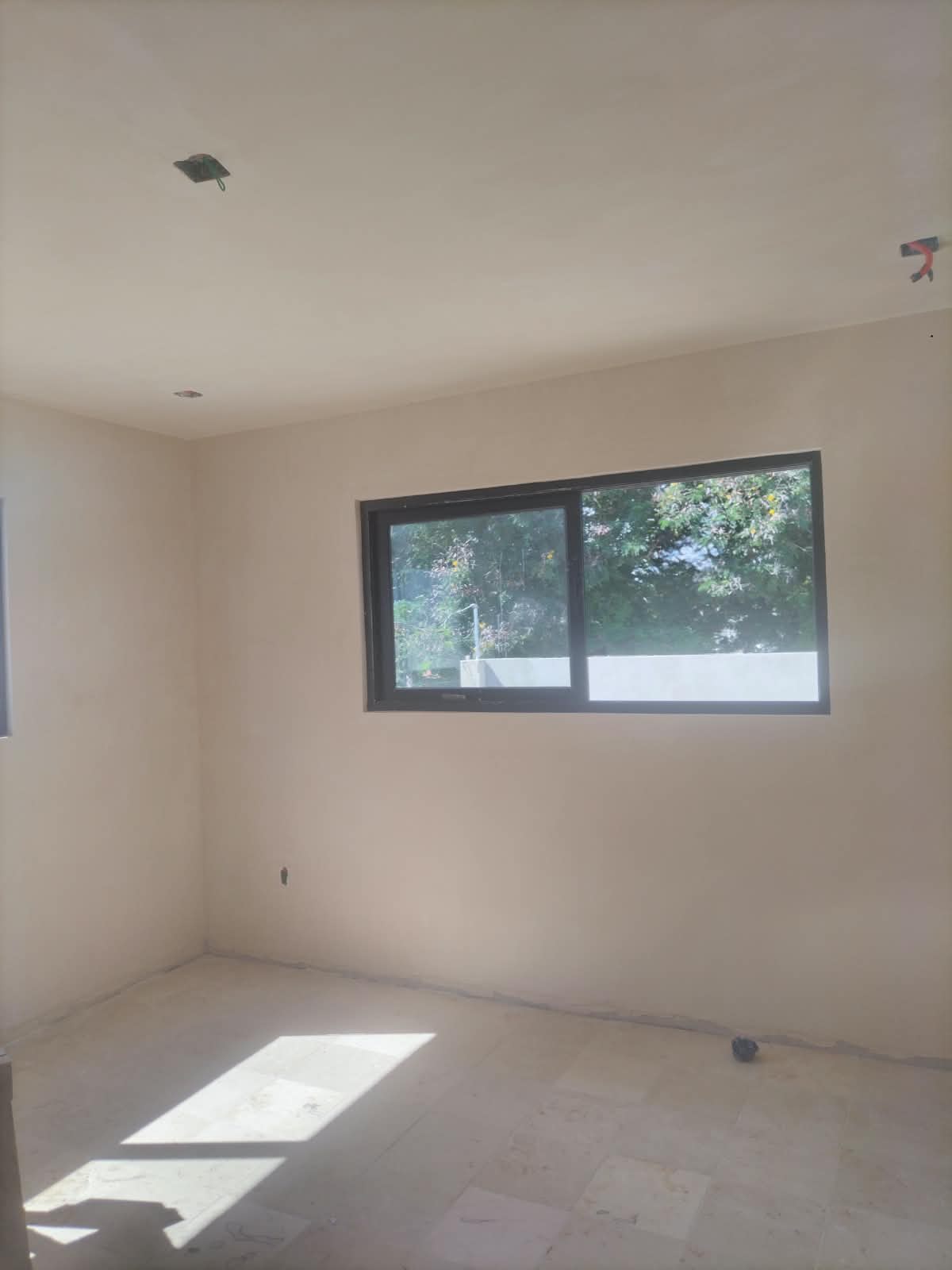 Habitación con pisos, muros y ventanas en etapa de acabados
